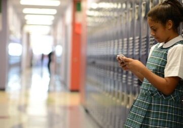 a girl holding a cellphone on the locker